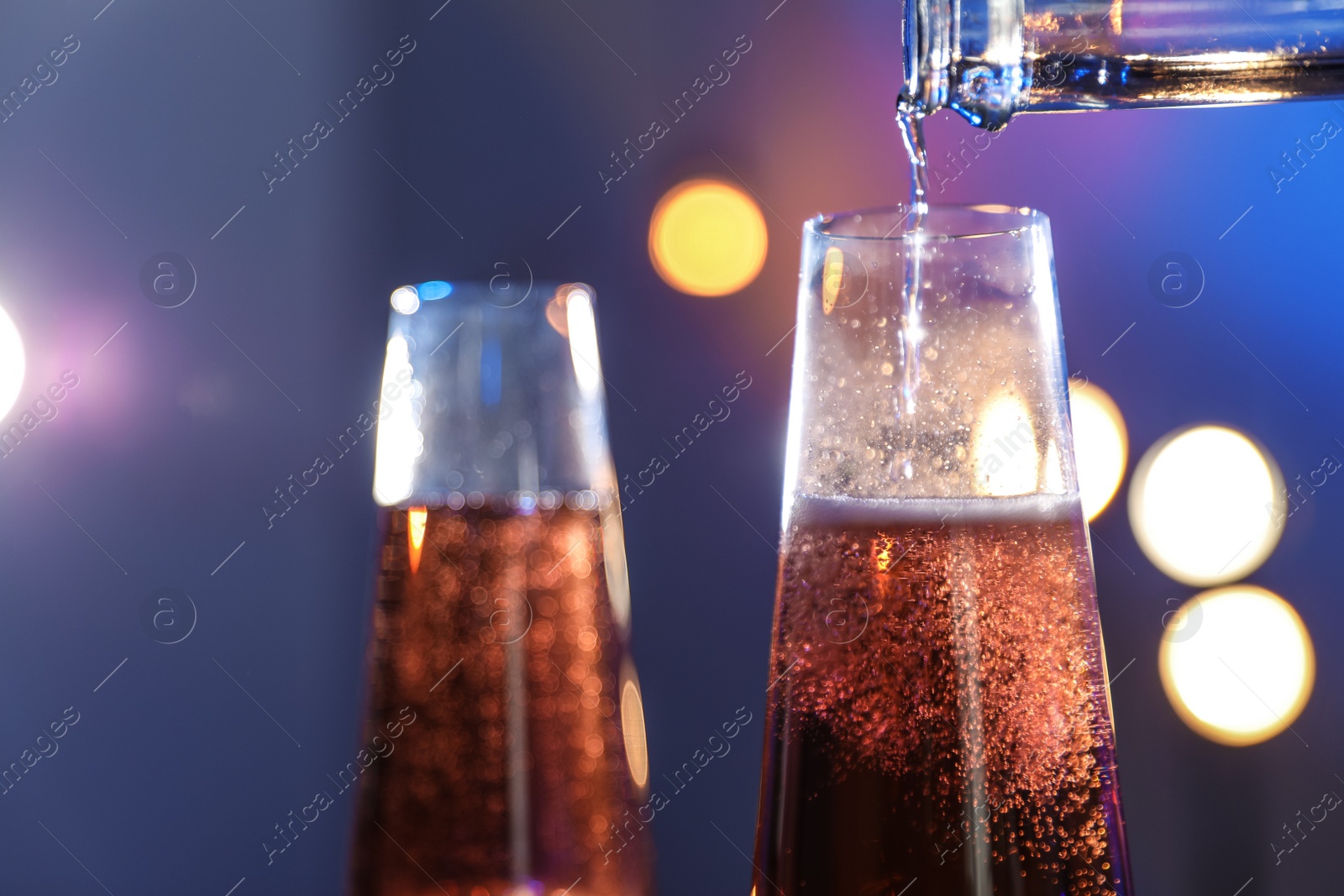 Photo of Rose champagne pouring from bottle into glass on color background, closeup. Space for text