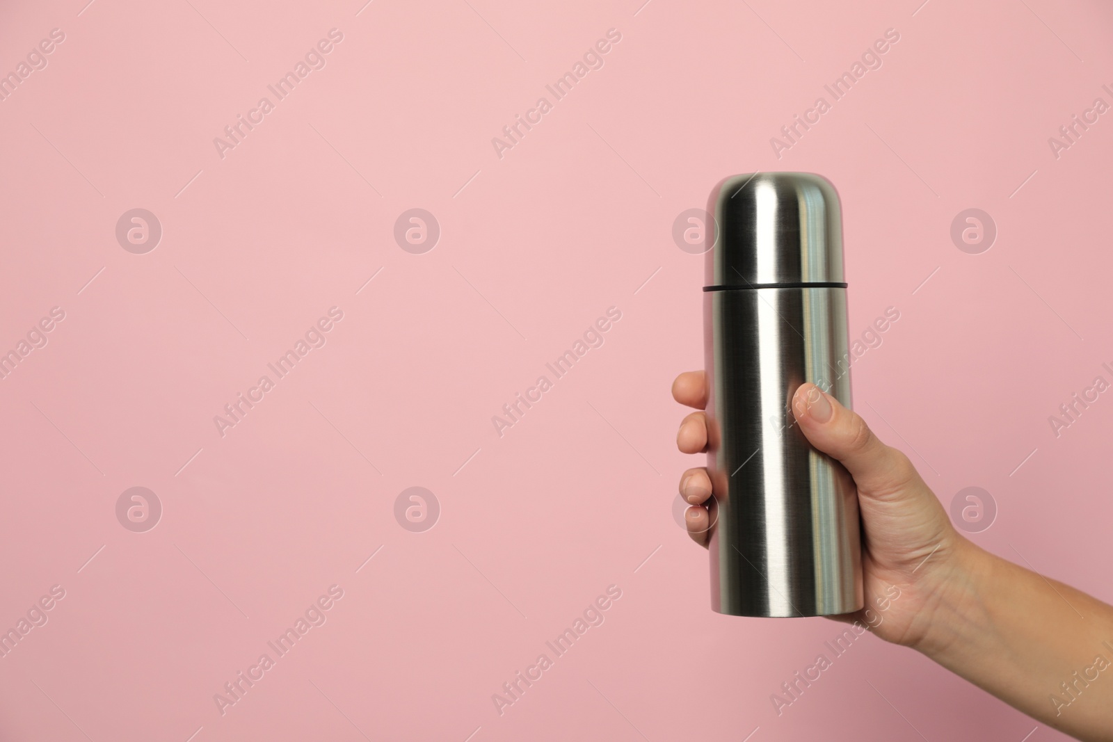 Photo of Woman holding modern thermos on pink background, closeup. Space for text