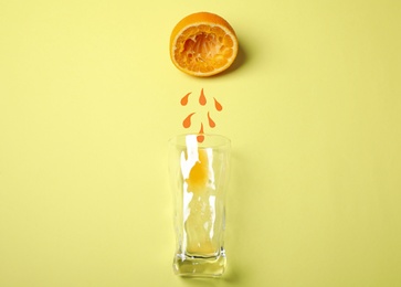 Photo of Composition with squeezed orange, paper drops and glass on yellow background, flat lay