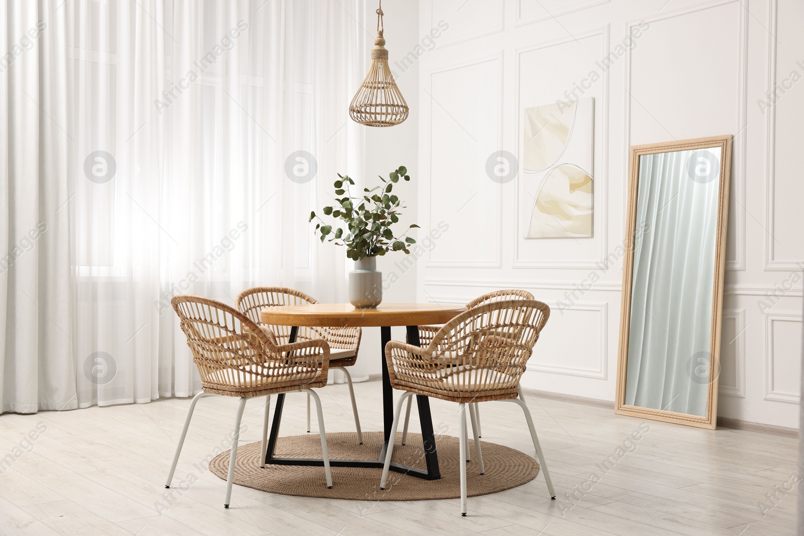 Photo of Dining room interior with comfortable furniture and eucalyptus branches