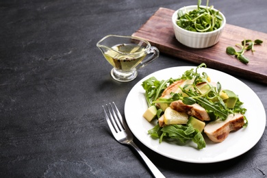 Photo of Delicious salad with chicken, lemon and arugula on black table. Space for text