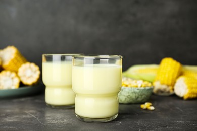 Photo of Tasty fresh corn milk in glass on grey table