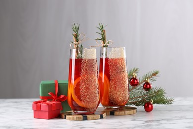 Photo of Christmas Sangria cocktail in glasses and festive decor on white marble table