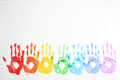 Photo of Handprints made with bright paints on white background, top view. Rainbow colors