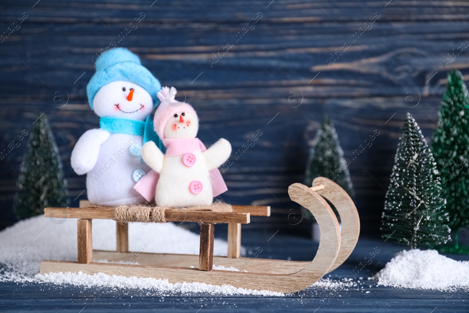 Photo of Sleigh with decorative snowmen on blue wooden background