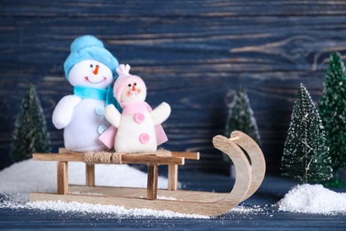 Sleigh with decorative snowmen on blue wooden background