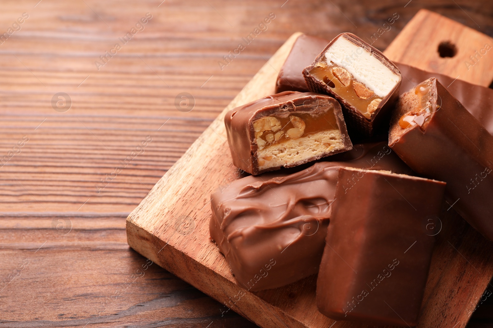 Photo of Tasty chocolate bars with nougat, caramel and nuts on table, closeup. Space for text