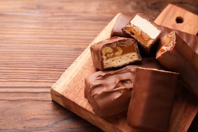Tasty chocolate bars with nougat, caramel and nuts on table, closeup. Space for text
