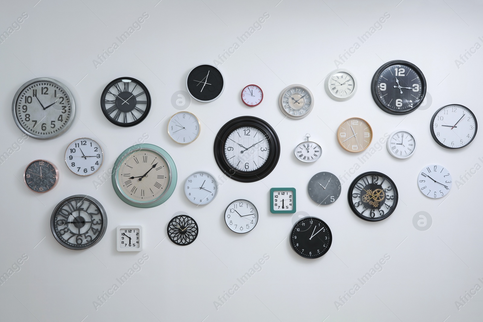 Photo of Collection of different clocks hanging on white wall