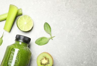 Green juice in bottle and fresh ingredients on light grey table, flat lay. Space for text