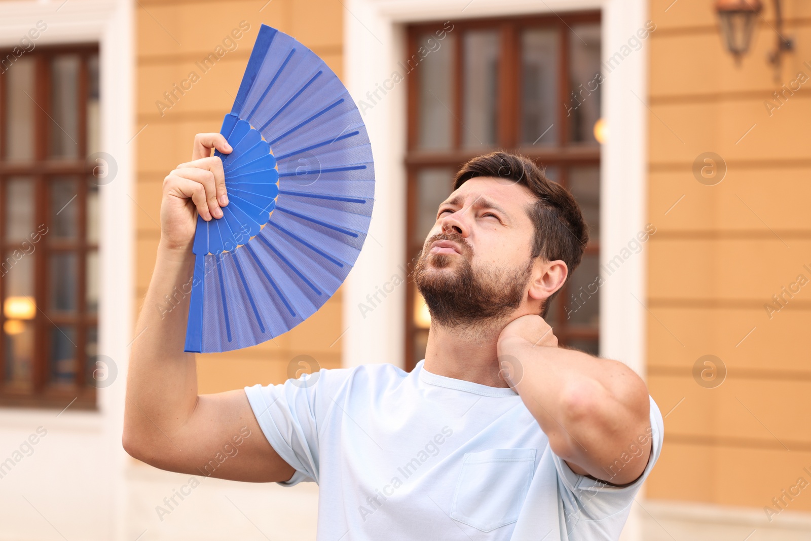 Photo of Man with hand fan suffering from heat outdoors