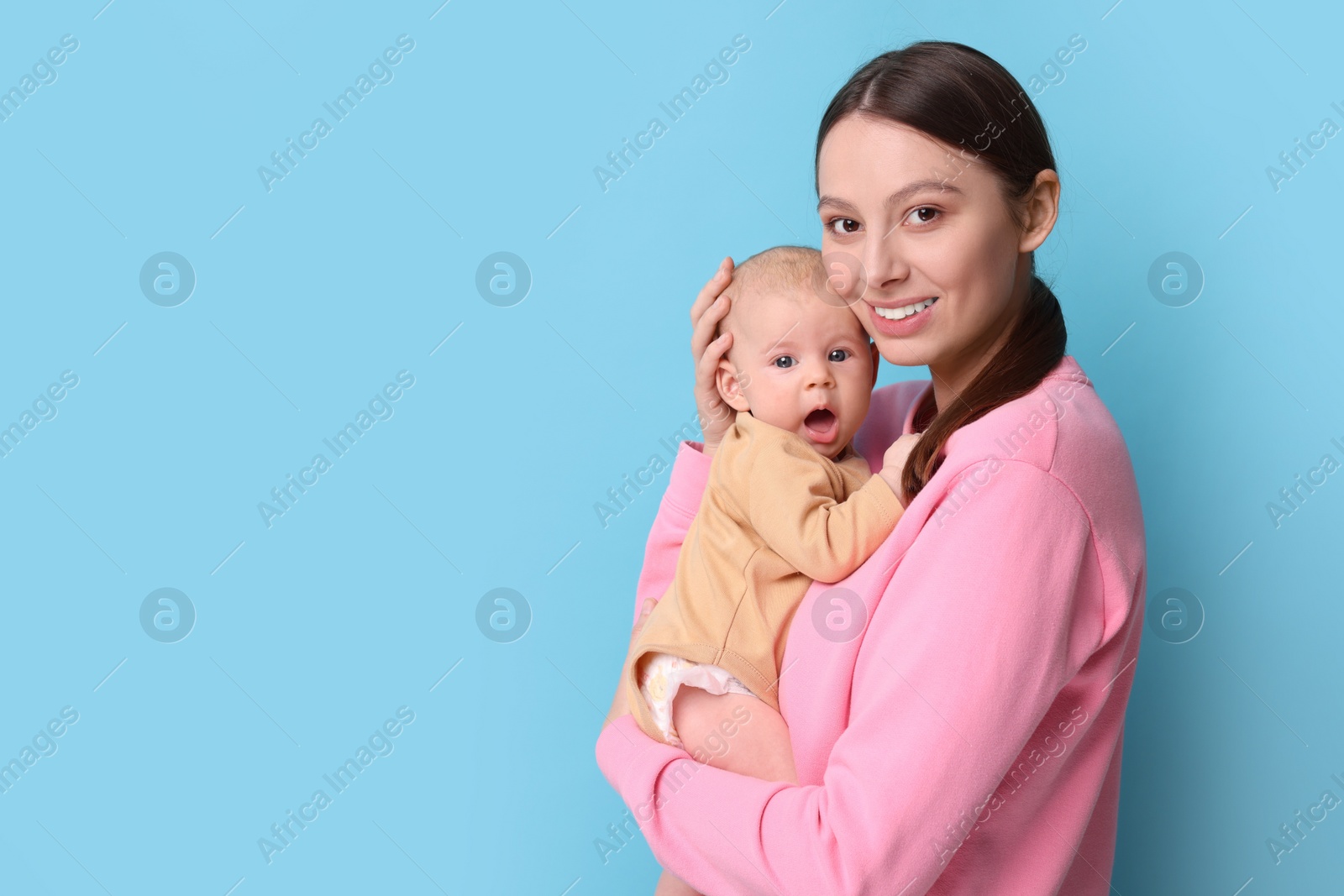 Photo of Happy mother with her cute baby on light blue background, space for text