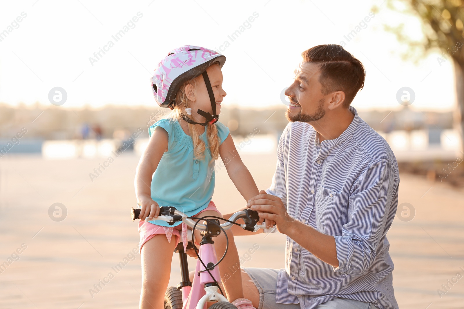 Photo of Father teaching daughter to ride bicycle on street