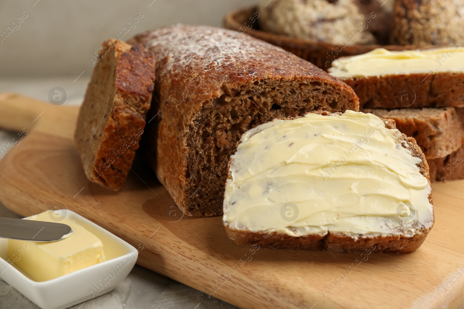 Photo of Tasty freshly baked bread with butter on table, closeup