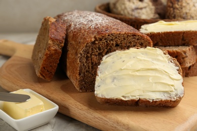 Photo of Tasty freshly baked bread with butter on table, closeup