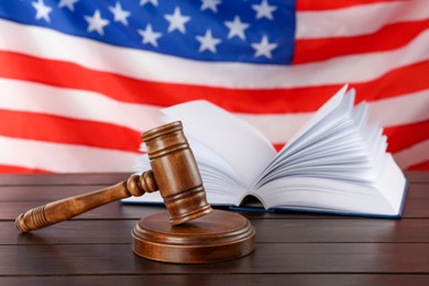Photo of Judge's gavel and book on wooden table against American flag
