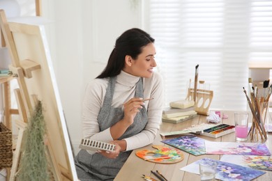 Photo of Young woman drawing on easel in studio