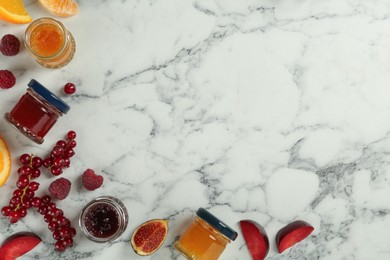 Photo of Jars of different jams and fresh ingredients on white marble table, flat lay. Space for text