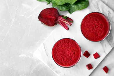 Photo of Glasses of fresh beet juice on marble board, top view