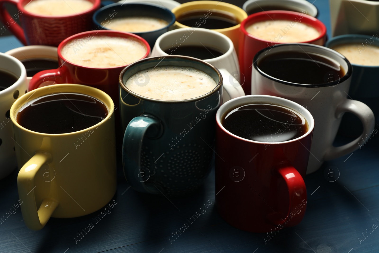 Photo of Many cups of different coffee drinks on blue wooden table