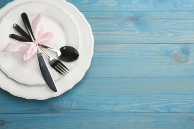 Photo of Beautiful table setting on light blue wooden background, top view with space for text. Valentine's Day dinner