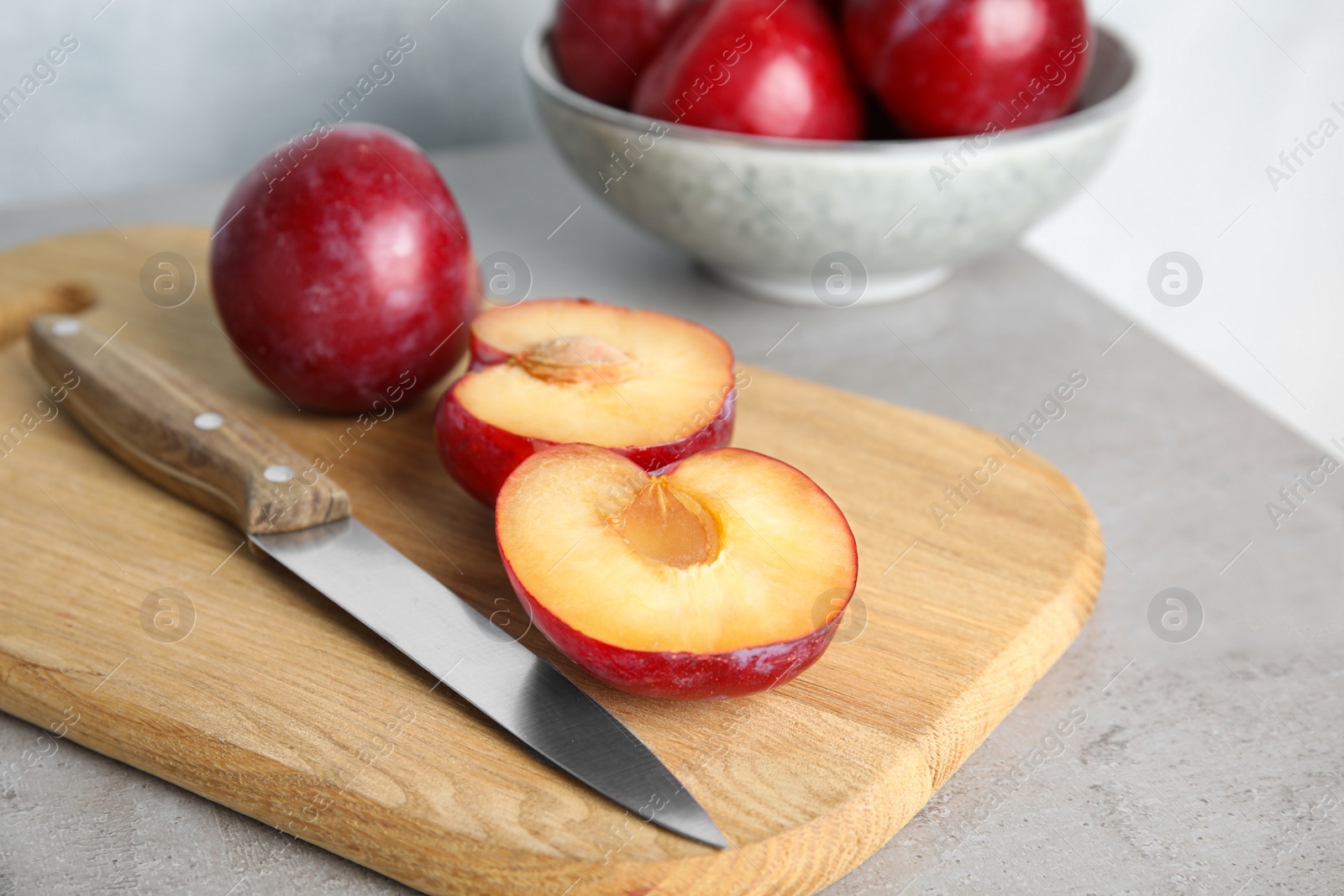 Photo of Delicious ripe plums on wooden board, closeup