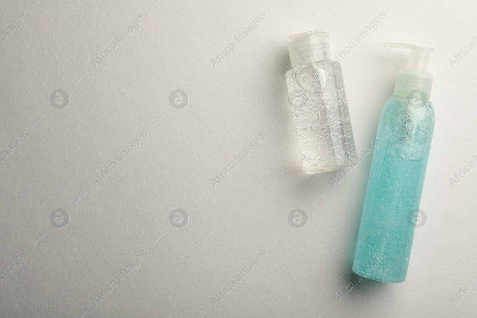 Photo of Bottles with different cosmetic gels on white background, flat lay. Space for text
