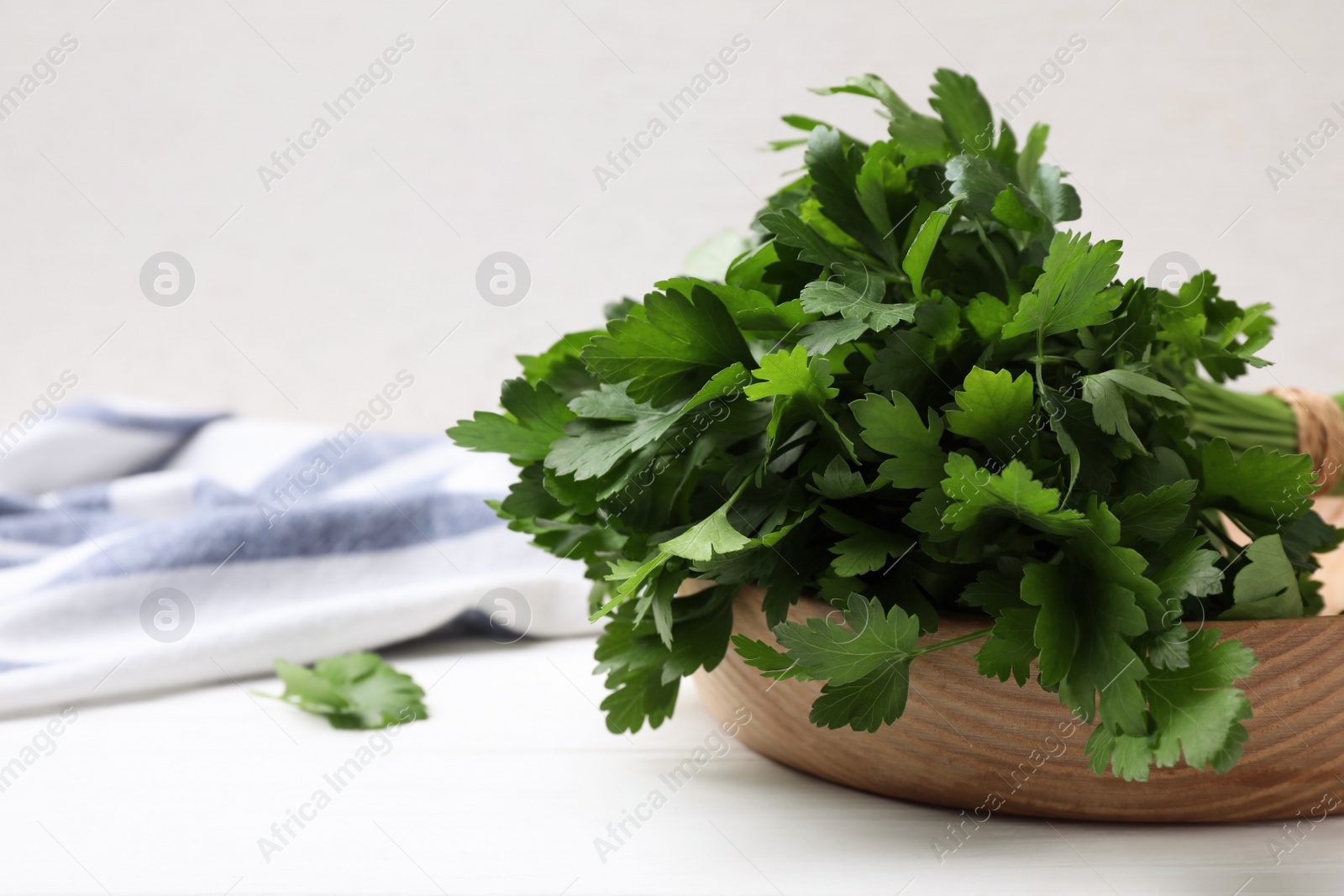 Photo of Bunch of fresh green parsley on white wooden table, closeup. Space for text