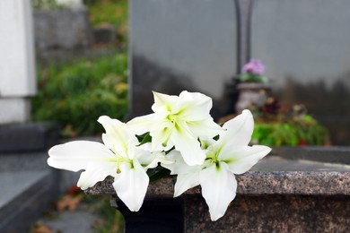 Photo of White lilies on tombstone outdoors, space for text. Funeral ceremony