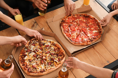 Photo of Young people eating delicious pizza at table, closeup