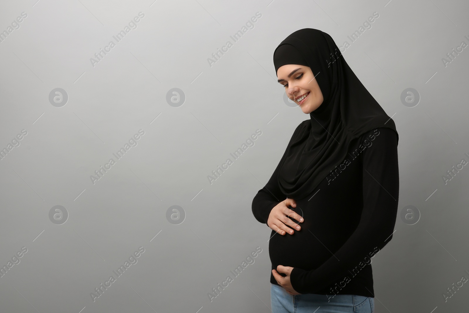 Photo of Portrait of pregnant Muslim woman in hijab on light gray background, space for text