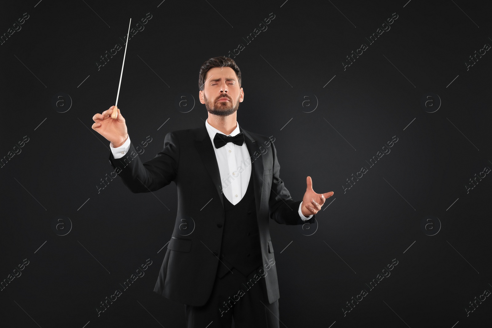 Photo of Professional conductor with baton on black background