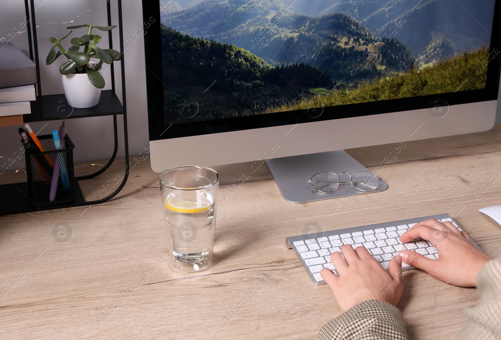 Photo of Woman working on computer at wooden table in room, closeup