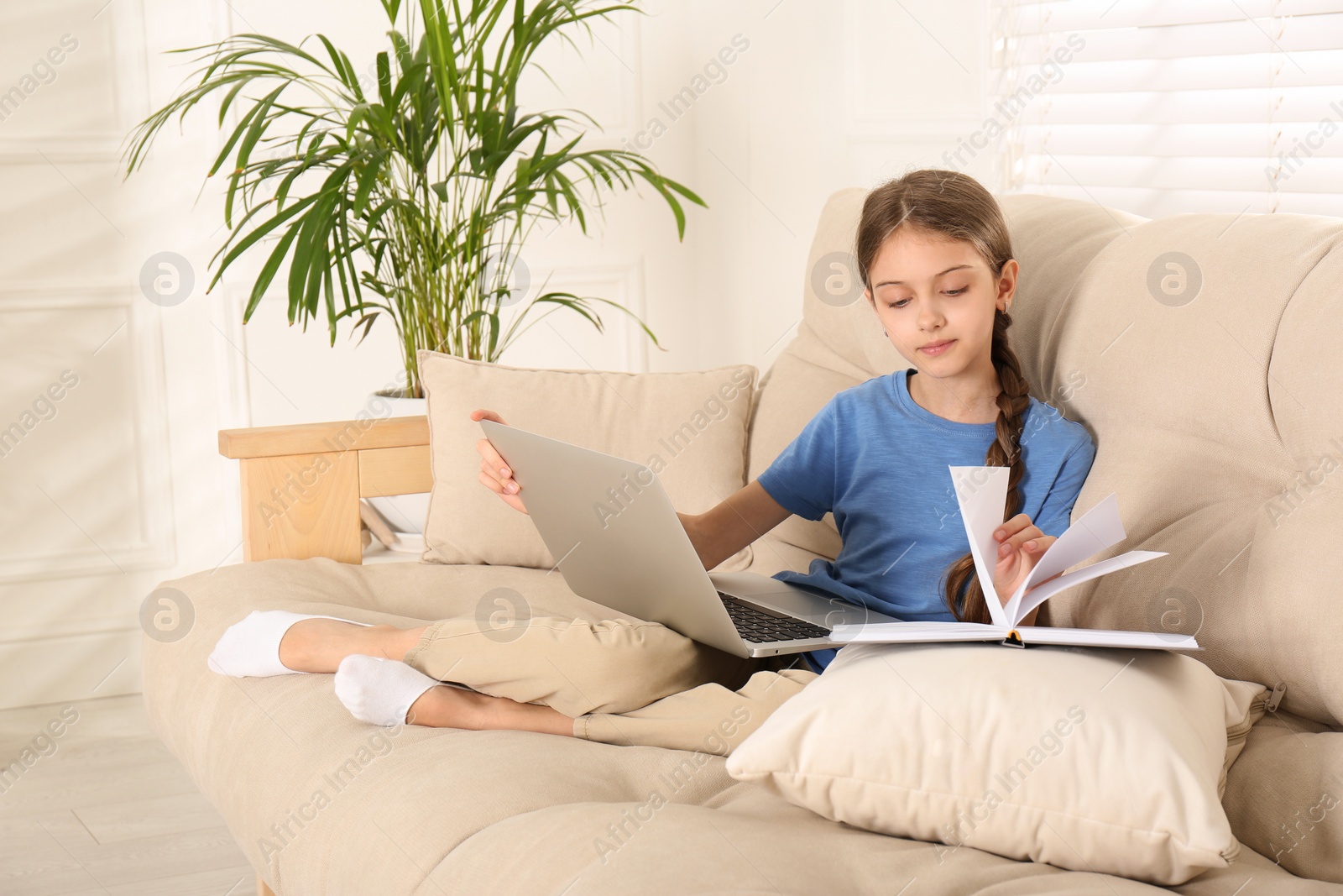 Photo of Girl with laptop and book on sofa at home