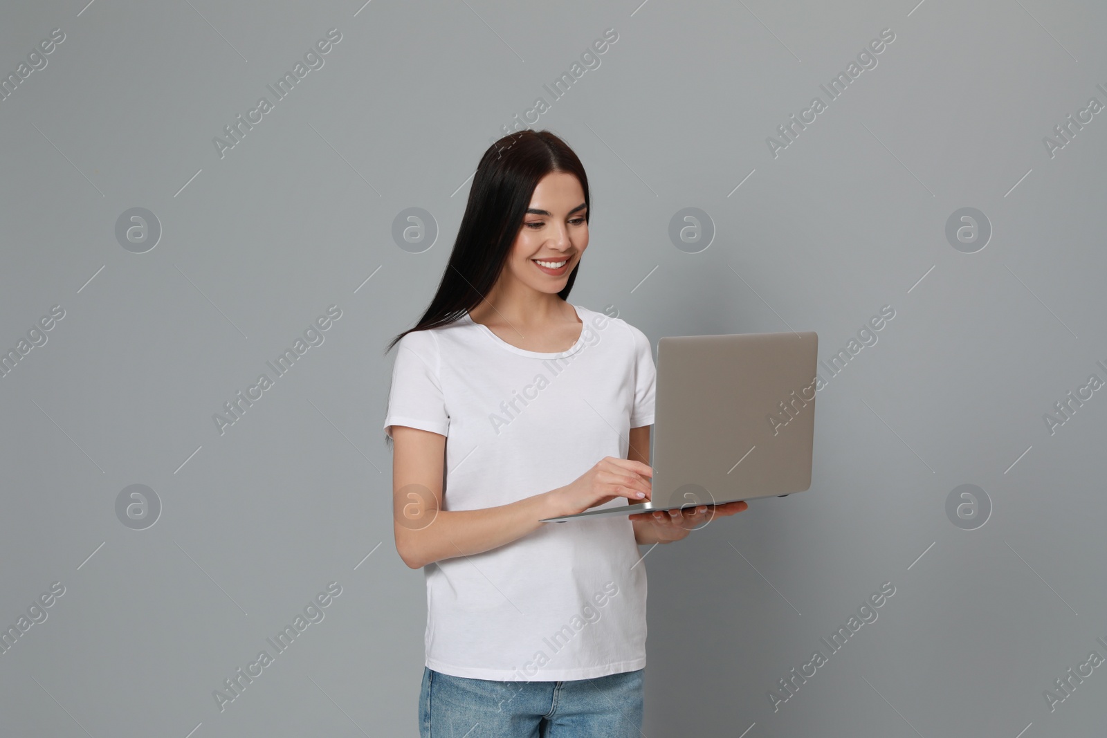 Photo of Young woman with modern laptop on light grey background