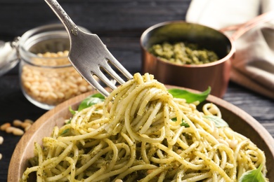 Fork with delicious basil pesto pasta over plate, closeup