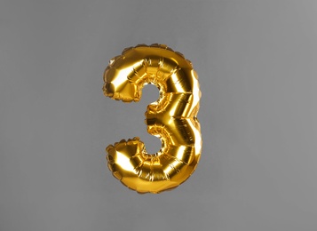 Golden number three balloon on grey background