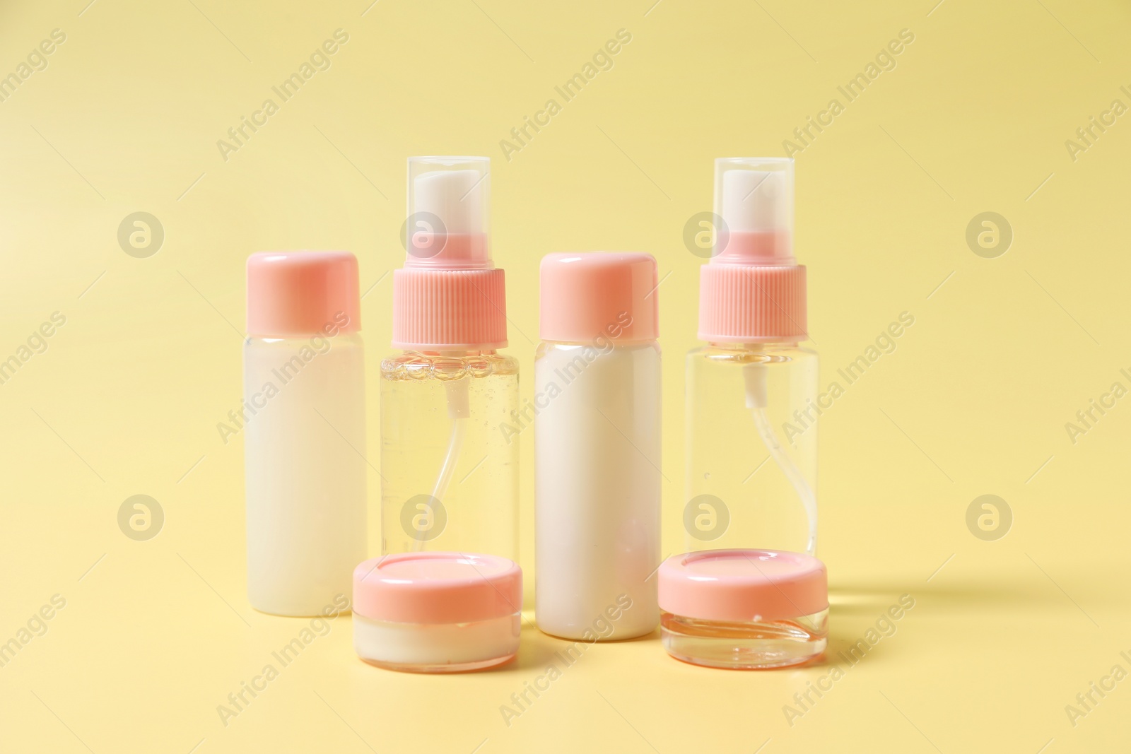 Photo of Cosmetic travel kit. Small containers of personal care products on yellow background