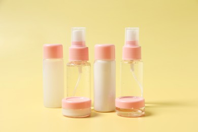 Photo of Cosmetic travel kit. Small containers of personal care products on yellow background