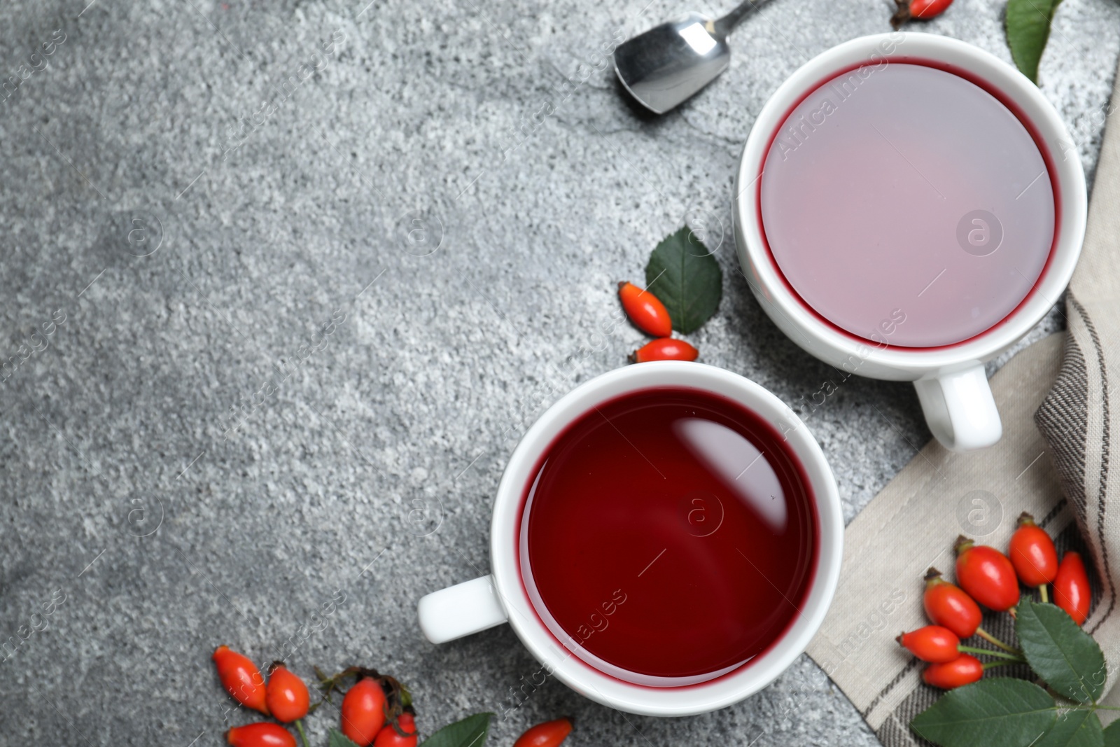 Photo of Fresh rose hip tea and berries on grey table, flat lay. Space for text