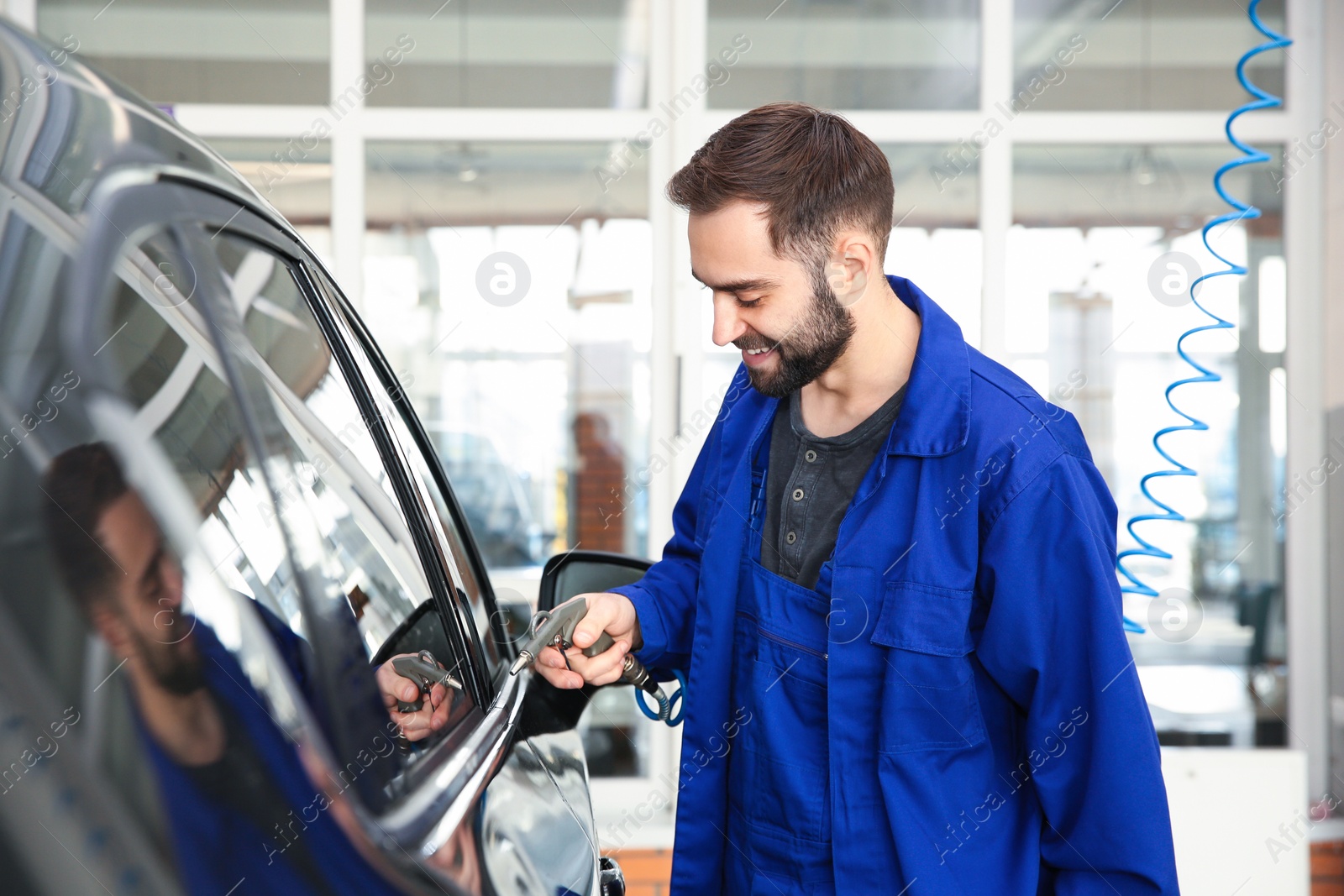 Photo of Worker using gun for auto cleaning at car wash