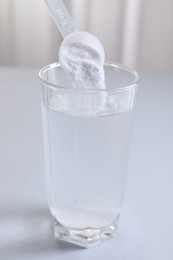 Photo of Adding baking soda into glass of water at white table