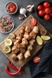 Photo of Delicious shish kebabs with sauce served on grey table, flat lay