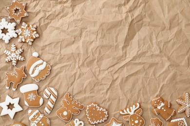 Photo of Different Christmas gingerbread cookies on crumpled parchment, flat lay. Space for text