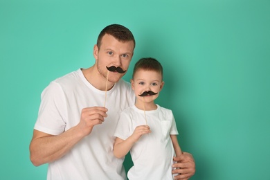 Photo of Happy dad and his son having fun on color background. Father's day celebration