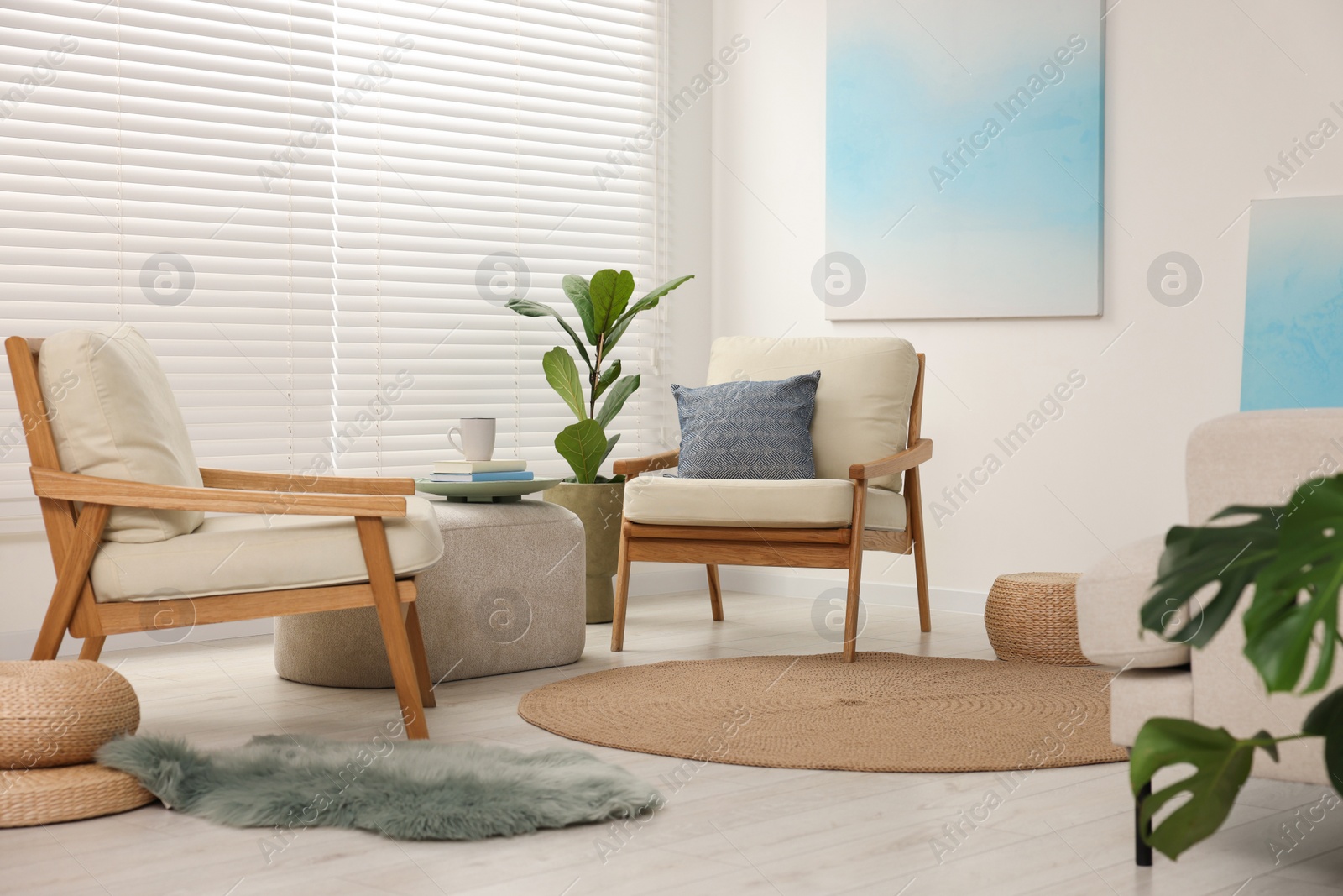 Photo of Comfortable beige armchairs, ottoman and houseplant in living room. Interior design