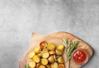 Photo of Tasty baked potato with aromatic rosemary and sauce served on grey textured table, flat lay. Space for text