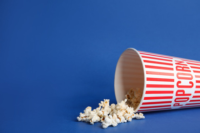 Tasty fresh pop corn on blue background, space for text