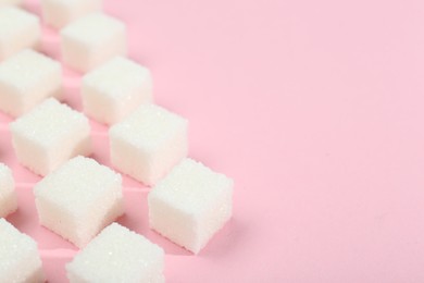 Photo of White sugar cubes on pink background, closeup. Space for text