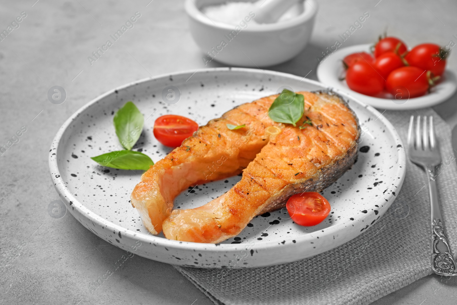 Photo of Plate with tasty salmon steak on grey background